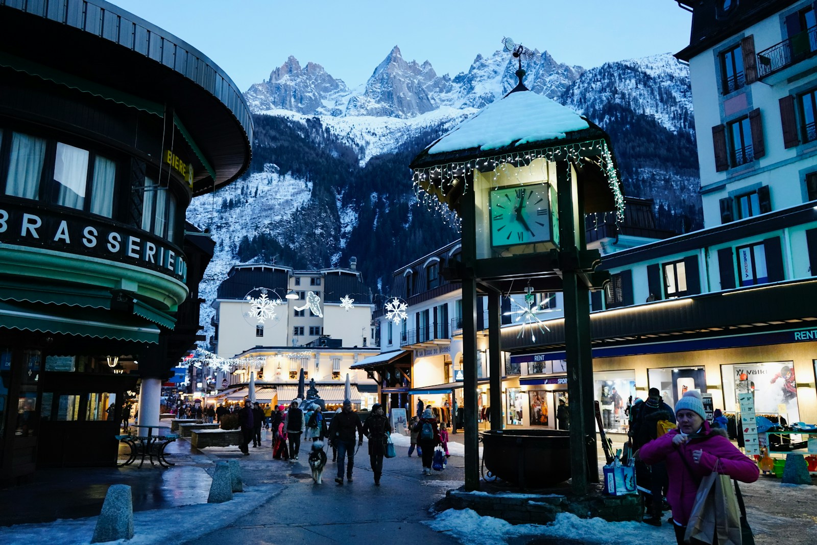 a clock tower in the middle of a town with mountains in the background